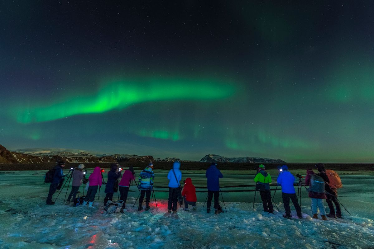 A group capturing the stunning aurora borealis over Iceland's icy landscape, perfect for travel and nature enthusiasts.