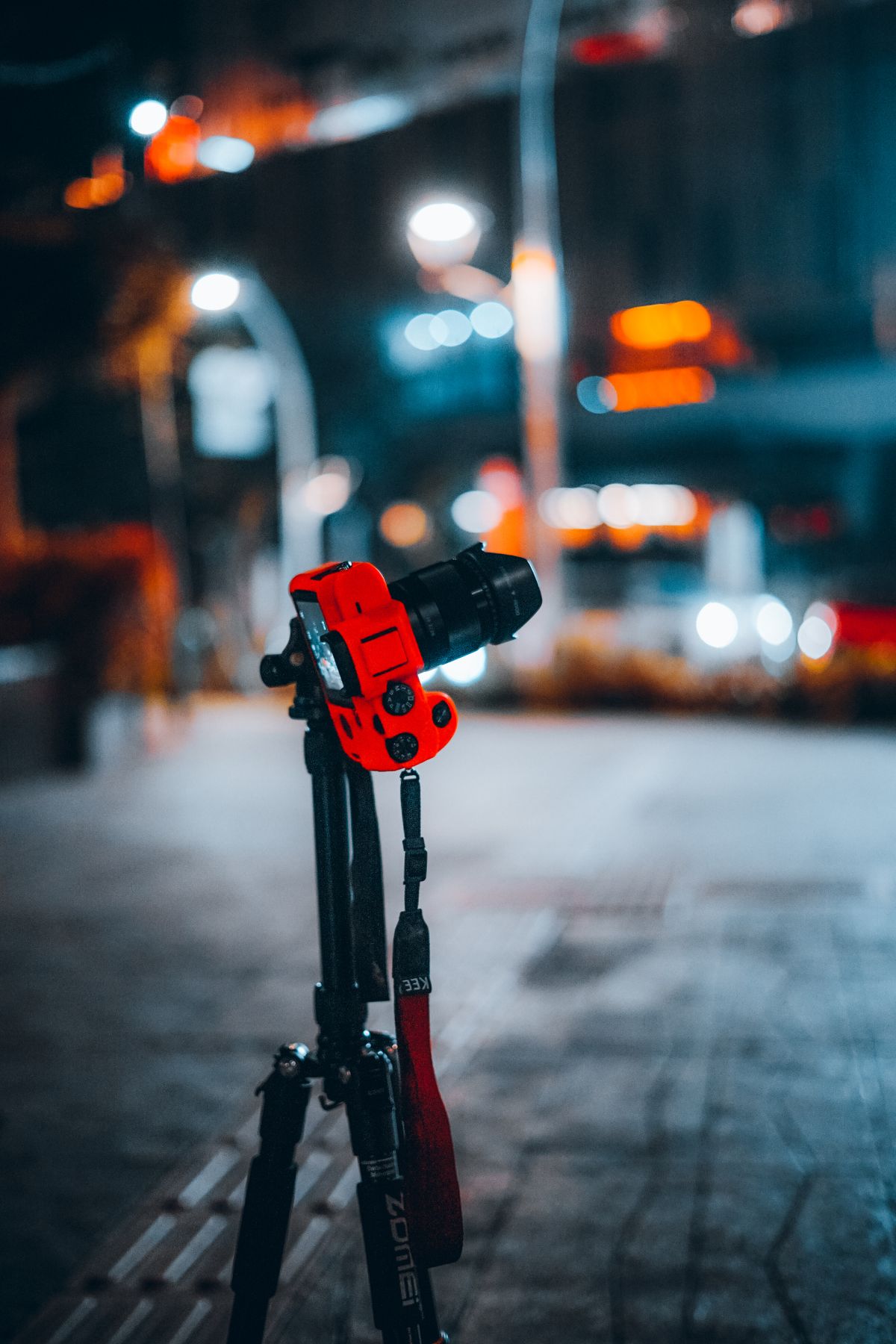 Dimly lit urban street scene with a camera on a tripod, capturing night photography.