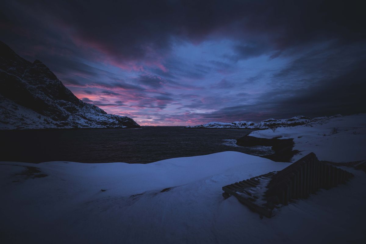 Stunning winter twilight scene with snow-covered mountains and colorful sky.